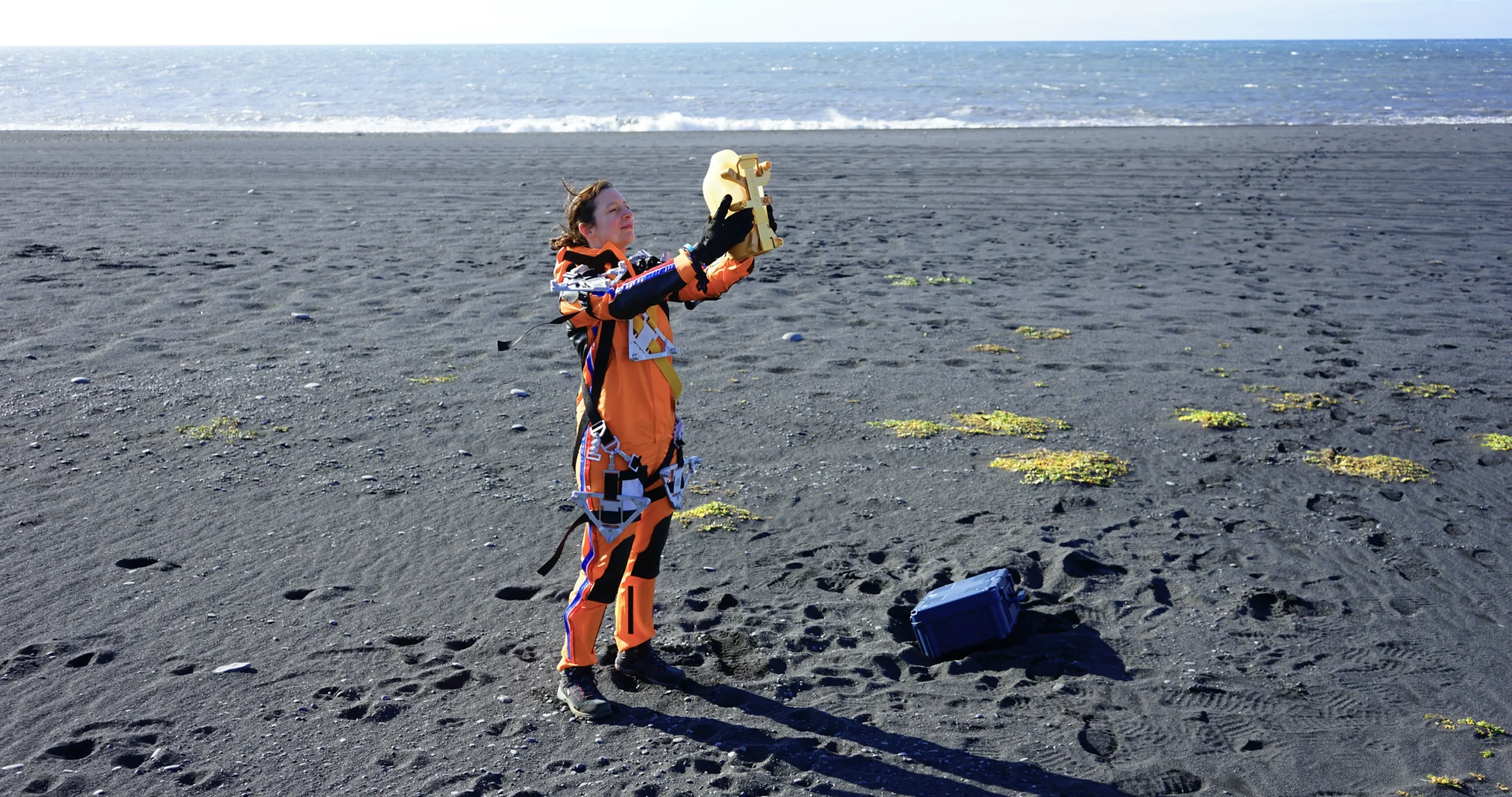 Moi en costume de Death Stranding sur une plage islandaise, tenant mon Bridge Baby en l'air