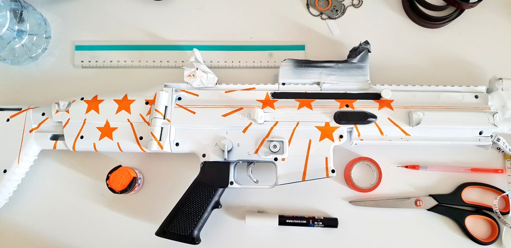 Un fusil en plastique en cours de modification pour ressembler à un modèle du jeu The Division 2 inspiré de la déclaration d'indépendance des États-Unis, avec des étoiles et des rayons orange